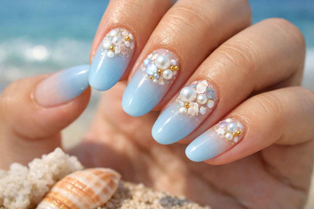 Close-up of Bali nails blue pastel ombre manicure with crushed seashell embellishments and pearl accents