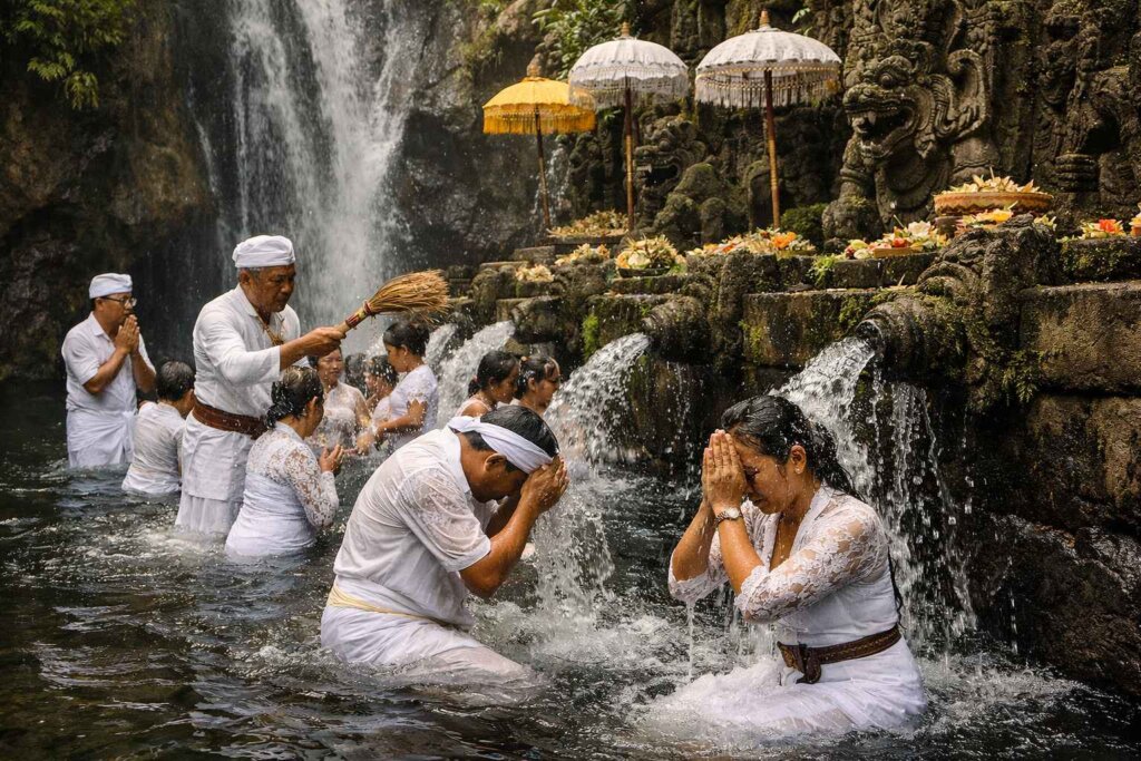 Taman Beji Griya sacred waterfall Ubud Bali, visitors in white sarongs during melukat purification ceremony