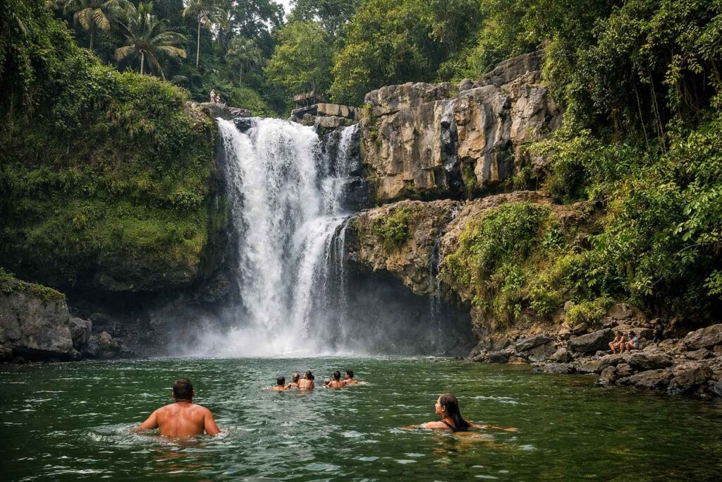 Tegenungan waterfall Ubud Bali with swimmers in green pool at base, surrounded by jungle