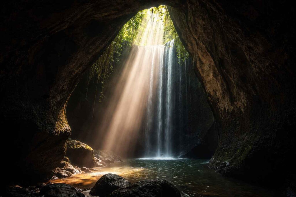 Ubud waterfal: Tukad Cepung hidden waterfall Ubud Bali, light shaft through cave ceiling onto falls below
